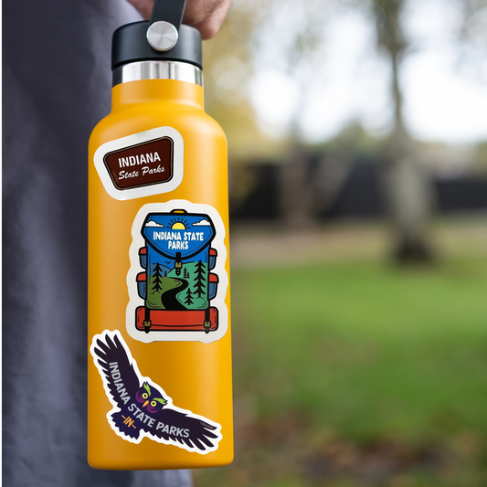 orange water bottle with Indiana State Parks stickers held by a person outdoors.