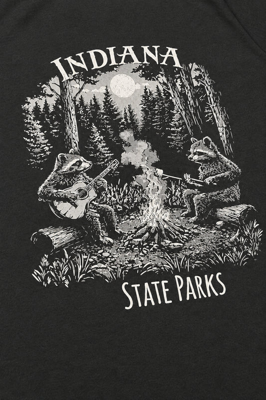 Close-up of a black T-shirt featuring a white graphic print of two raccoons by a campfire under the words 'INDIANA STATE PARKS'.