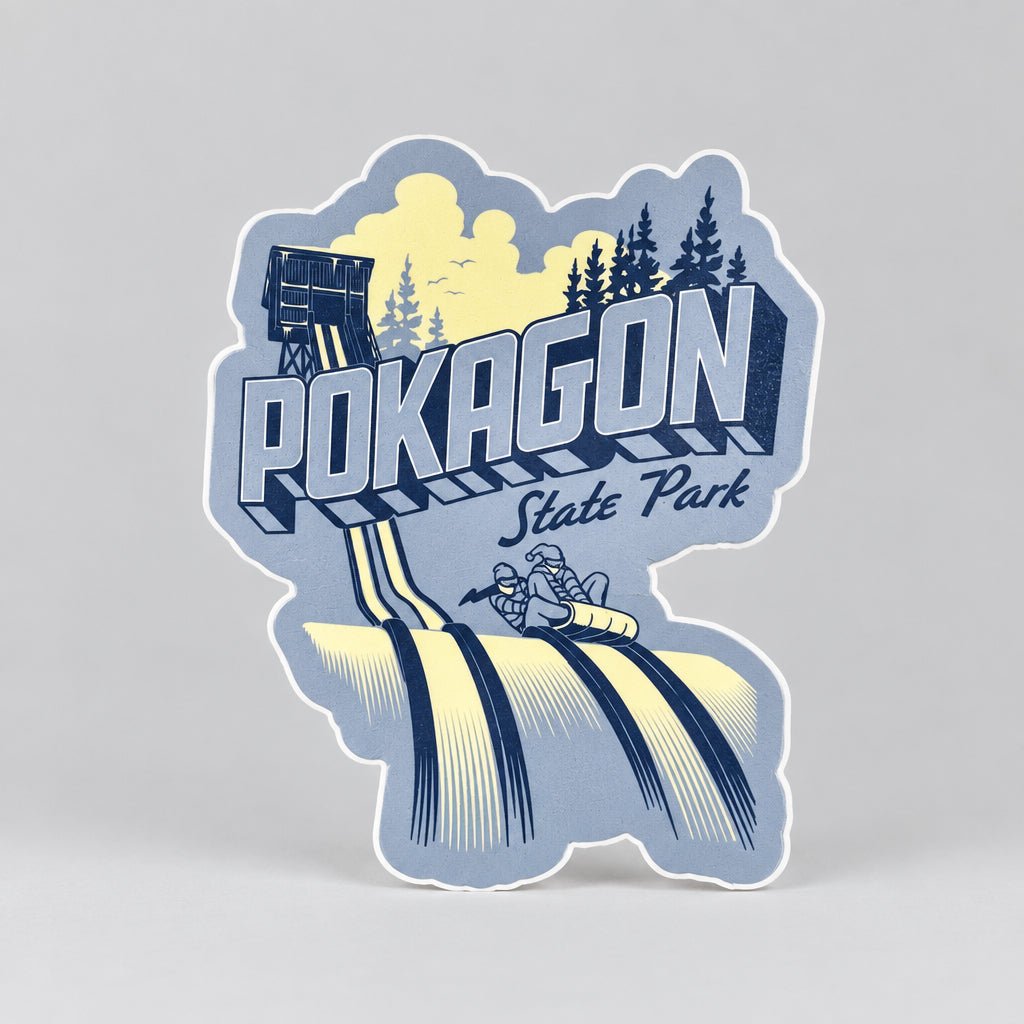 A blue sticker showing a toboggan tower, evergreen trees, and two people riding a toboggan down icy tracks, with the text “Pokagon State Park.”