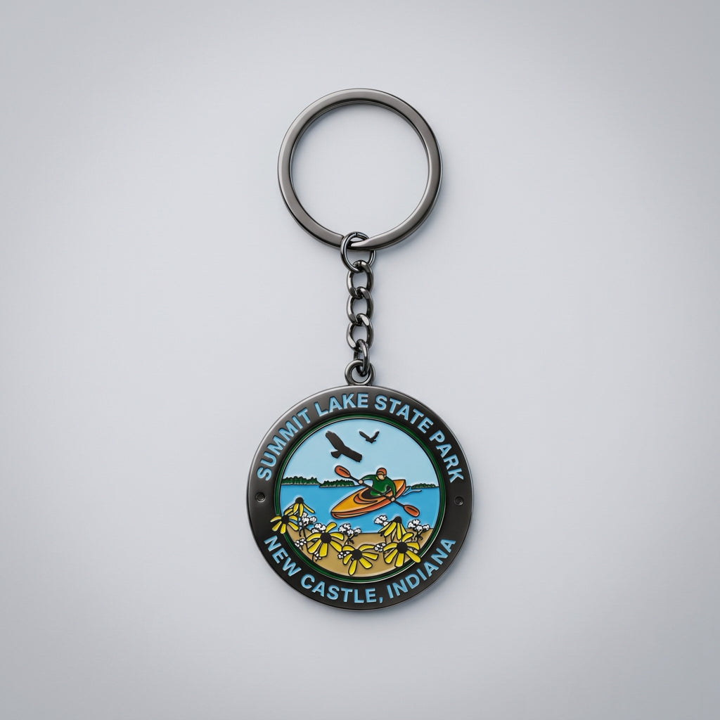 Round metal keychain showing a kayaker on a lake with wildflowers in the foreground and birds in the sky, labeled “Summit Lake State Park New Castle, Indiana.”