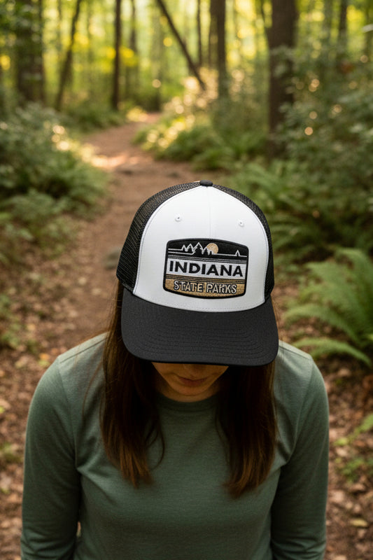 Black and white cap with 'Indiana State Parks' logo on a person in the woods