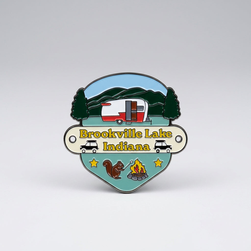 Enamel‑style hiking medallion with a camper in front of hills, cars, a squirrel, stars, and a campfire, labeled “Brookville Lake Indiana.”