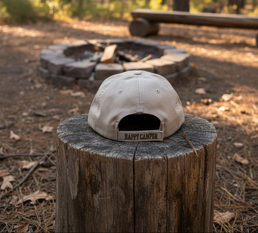 Beige cap with 'Happy Camper' text on a white surface with white background