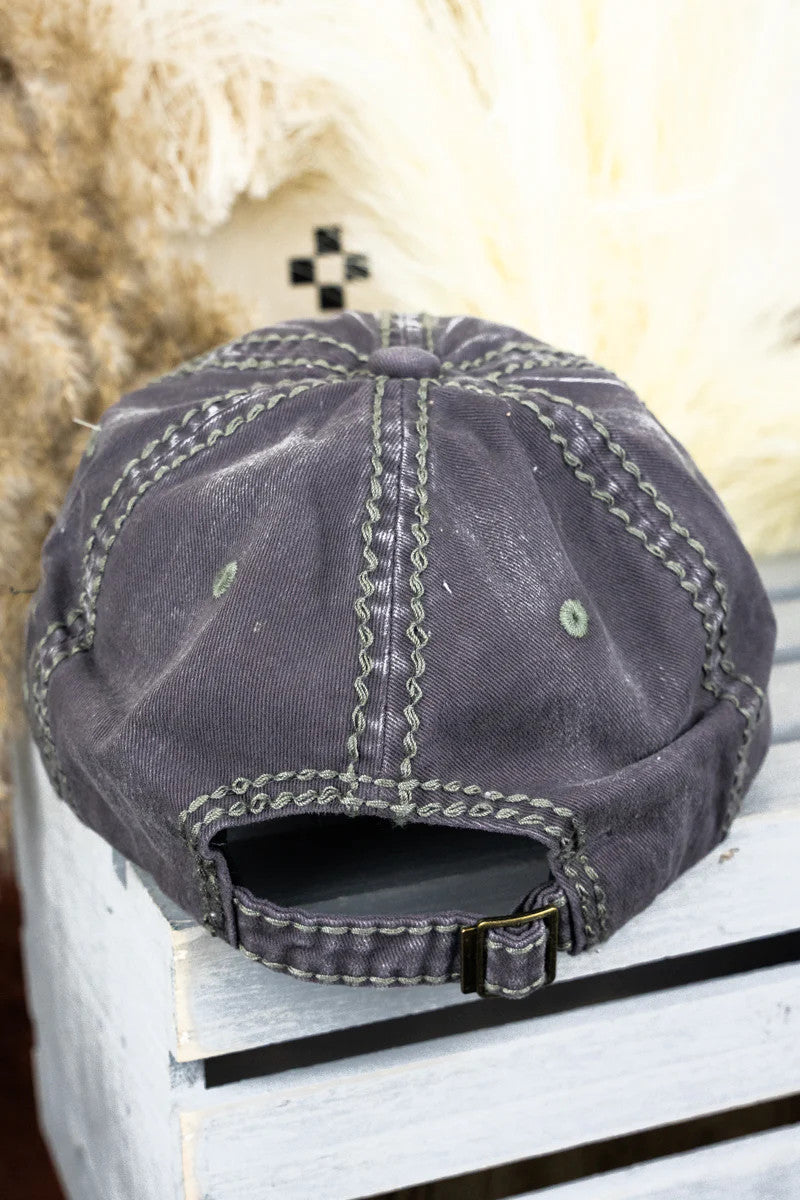 Back of a grey cap on a white surface with a blurred background