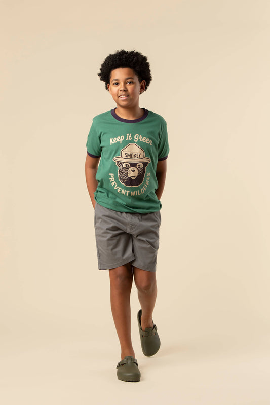 Child wearing a green t-shirt with a bear graphic and text on a beige background