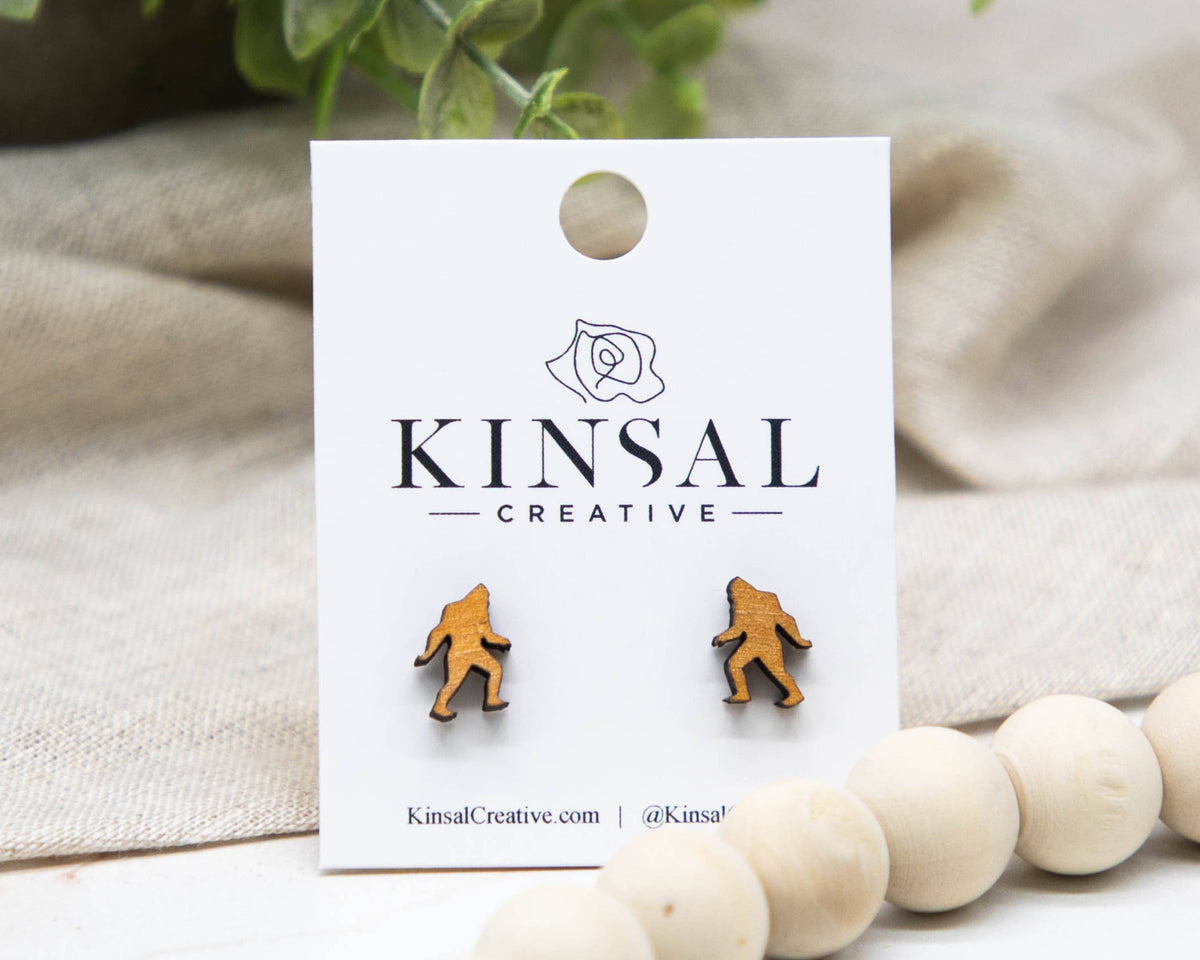 Sasquatch earrings on a Kinsal Creative branded card with a beige fabric background