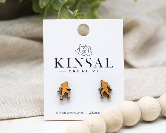 Sasquatch earrings on a Kinsal Creative branded card with a beige fabric background