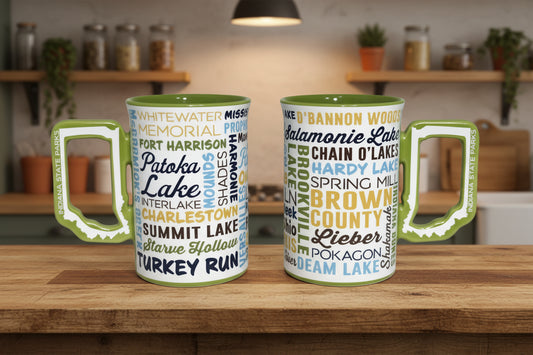 Two mugs with state parks text and green Indiana shaped handles on a white background