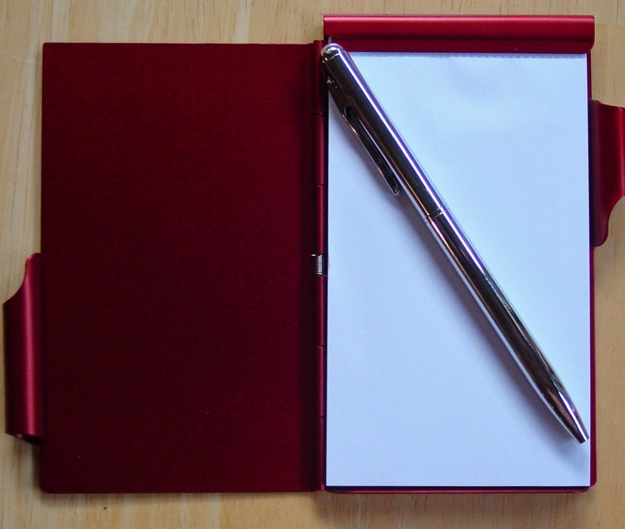 Red notebook with a pen on a wooden surface