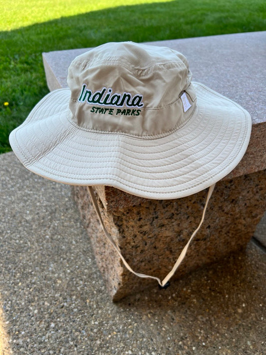 A beige wide-brim bucket hat with 'Indiana State Parks' embroidered on the front, resting on a stone bench outdoors.