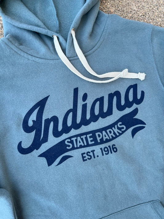 A close-up of a heathered slate blue hoodie featuring a navy blue graphic print that reads 'Indiana State Parks Est. 1916' on the chest, with white drawstrings.