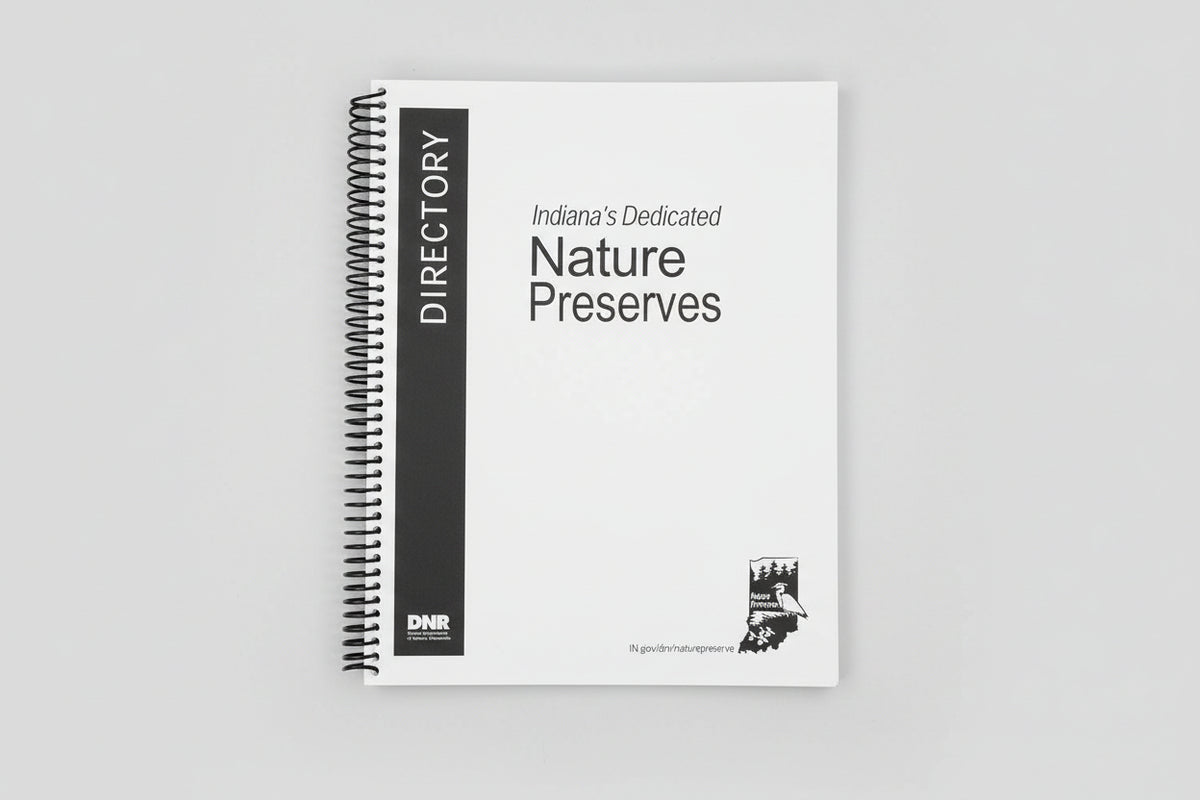 A spiral-bound book titled 'Directory Indiana's Dedicated Nature Preserves' with a black vertical spine panel and DNR logo, photographed on a gray textured surface.