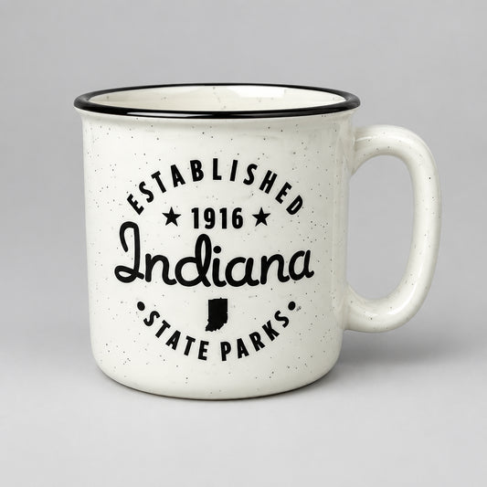 A white speckled mug with a black rim and black printed text reading 'ESTABLISHED 1916 Indiana STATE PARKS' on a gray countertop.