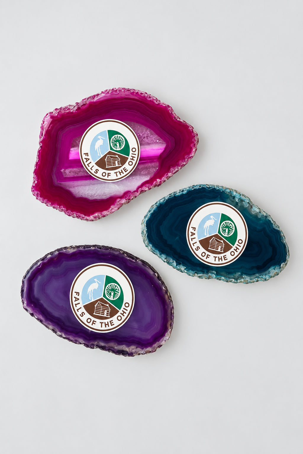 Three colorful agate slice magnets with the Falls of the Ohio logo on a light background.