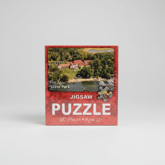 Jigsaw puzzle box with scenic image and text on a neutral background