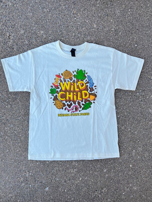 A cream short-sleeve youth t-shirt with a colorful 'Wild Child' graphic print, laid flat on a gray asphalt surface.