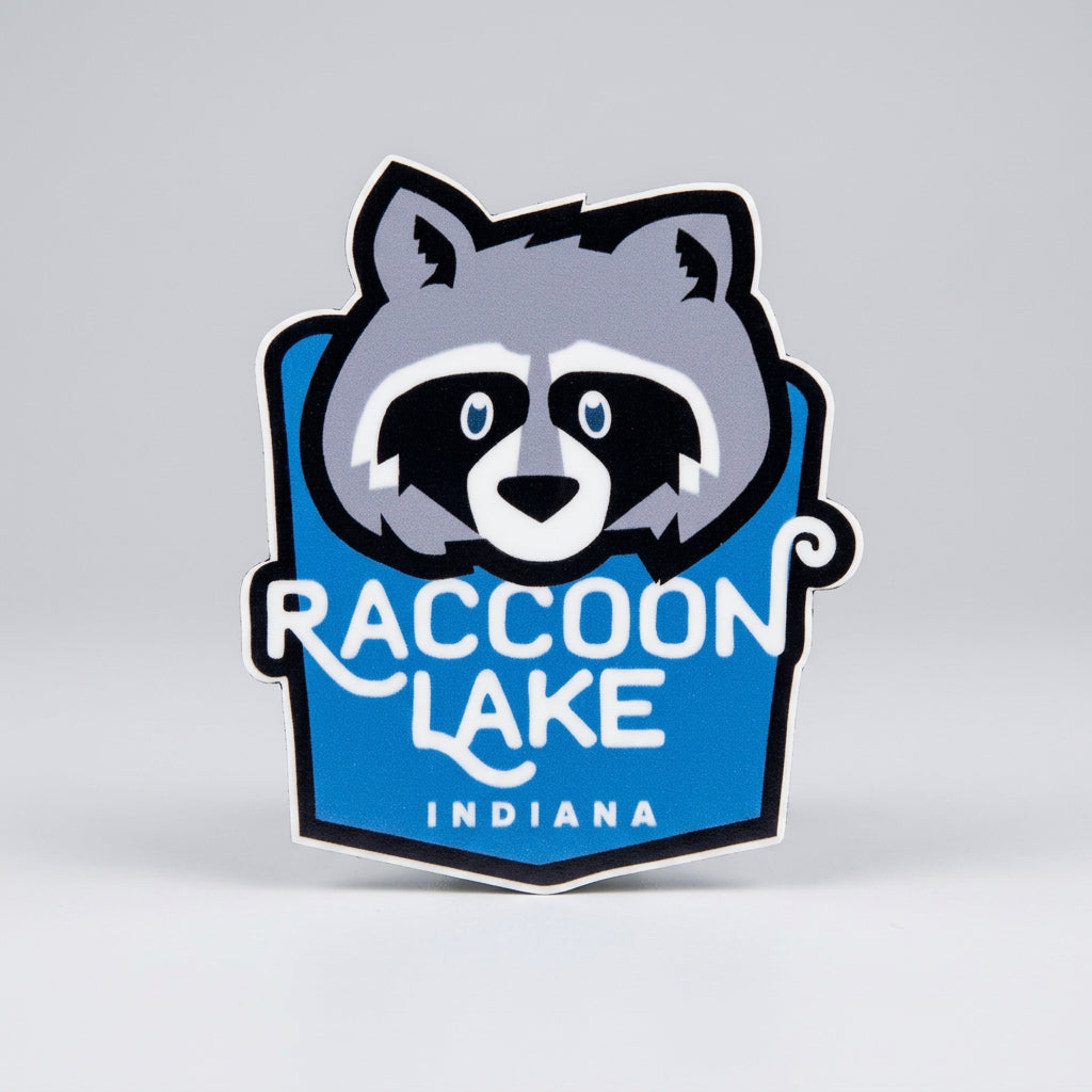 Die‑cut sticker with a stylized raccoon face above the text “Raccoon Lake Indiana” on a blue background.