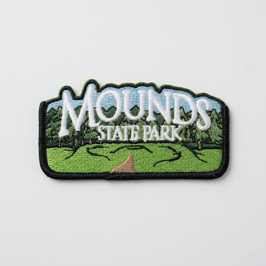 Embroidered patch showing green mounds, a path, and trees with large text reading “Mounds State Park.”