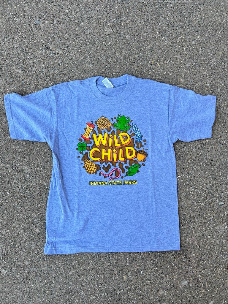 A gray short-sleeve youth t-shirt with a colorful 'Wild Child' graphic print, laid flat on a gray asphalt surface.