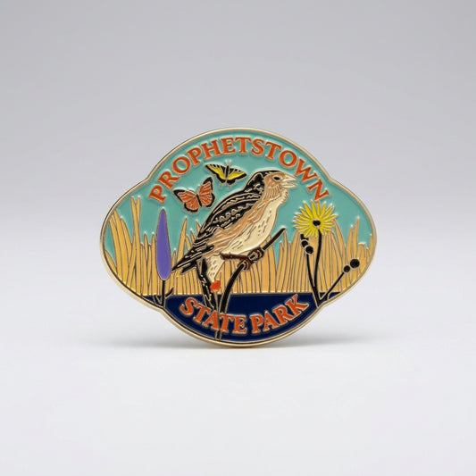 Enamel‑style magnet showing a bird perched in tall grasses with butterflies and wildflowers, surrounded by the text “Prophetstown State Park.”