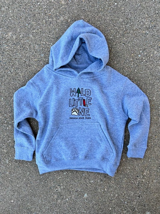 A youth grey pullover hoodie with a front pocket and a graphic print reading 'WILD LITTLE ONE' with a paw print, laid flat on a gray asphalt surface.