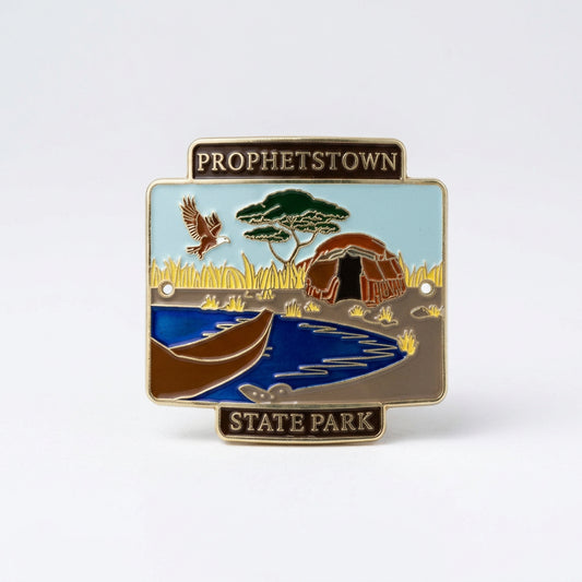 Enamel‑style hiking medallion showing a canoe on the water with tall grasses, wildlife, and a structure in the background, labeled “Prophetstown State Park.”