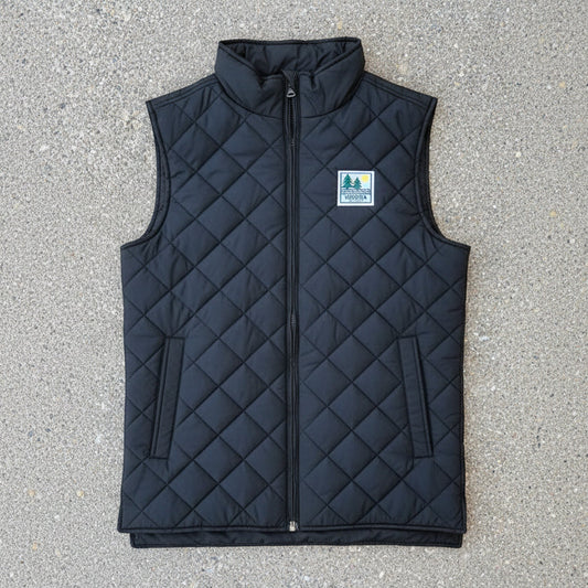 A black diamond-quilted zip-up vest with a stand-up collar and a small green and white 'Indiana State Parks' patch on the left chest, laid flat on a gray concrete surface.