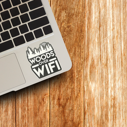 Laptop with 'Woods Over WiFi' sticker on a wooden surface