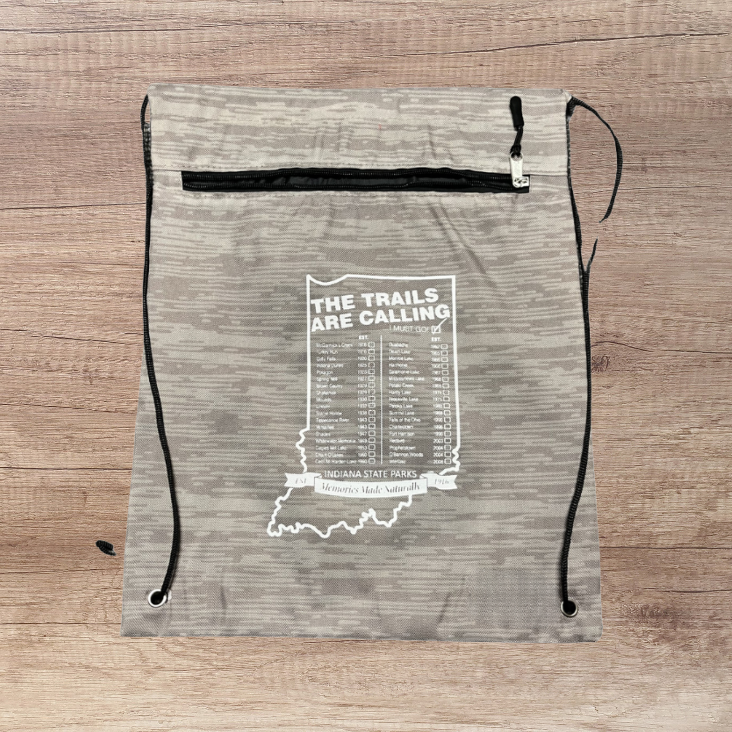 Drawstring bag with 'The Trails Are Calling' text and Indiana state outline on a wooden surface