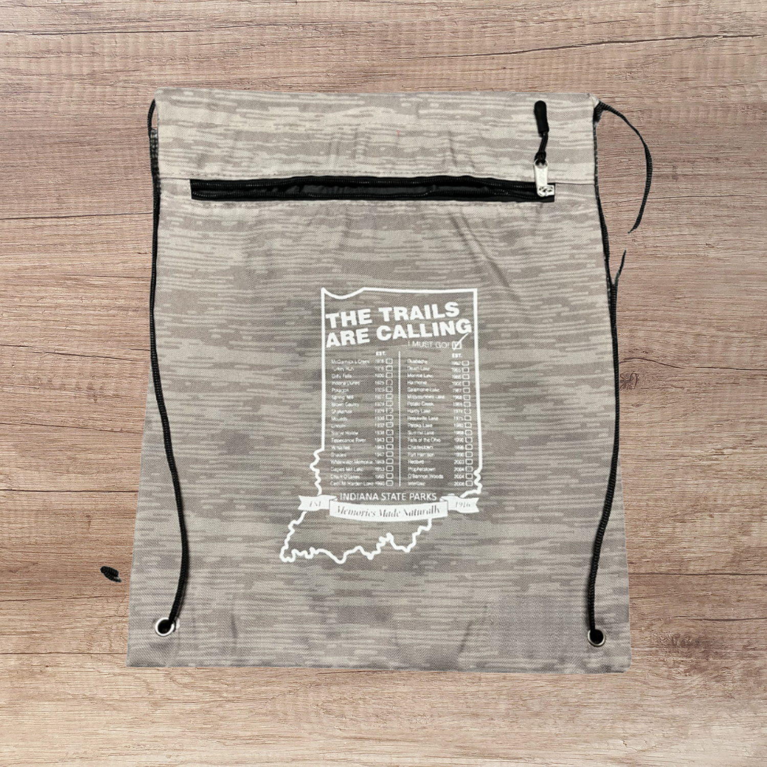 Drawstring bag with 'The Trails Are Calling' text and Indiana state outline on a wooden surface