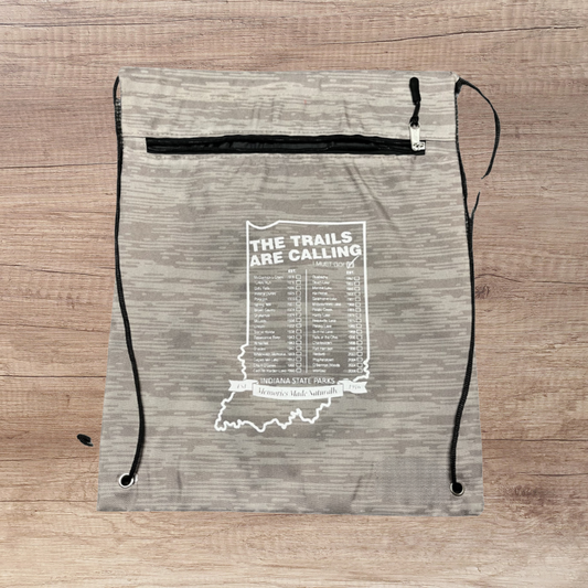 Drawstring bag with 'The Trails Are Calling' text and Indiana state outline on a wooden surface