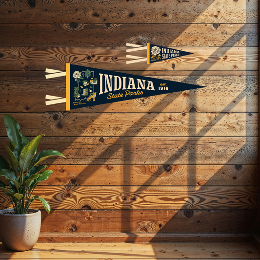 A navy blue Indiana State Parks 1916 pennant flag with yellow and white details, displayed on a rustic wooden wall above a potted plant.