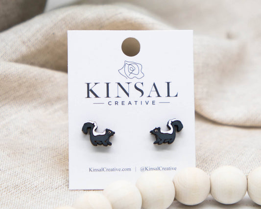 Black and white squirrel-shaped earrings on a Kinsal Creative card against a beige background