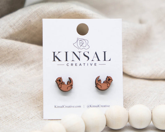 otter earrings on a white card with a beige background