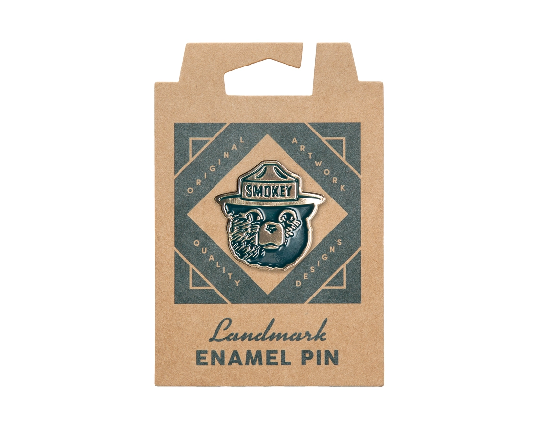 Kraft paper packaging with an enamel pin featuring a bear design and 'Smoky' branding.