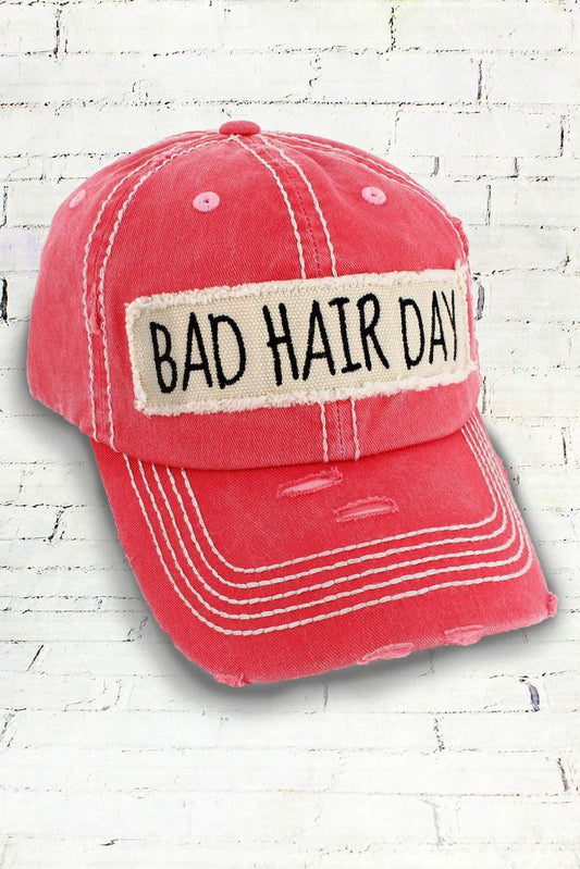 Salmon pink colored cap with 'Bad Hair Day' patch on a white brick background