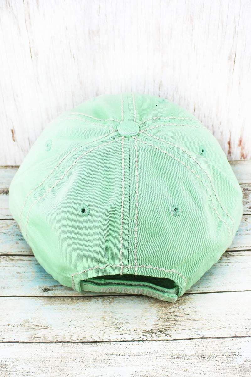 Back of a mint green baseball cap on a wooden surface
