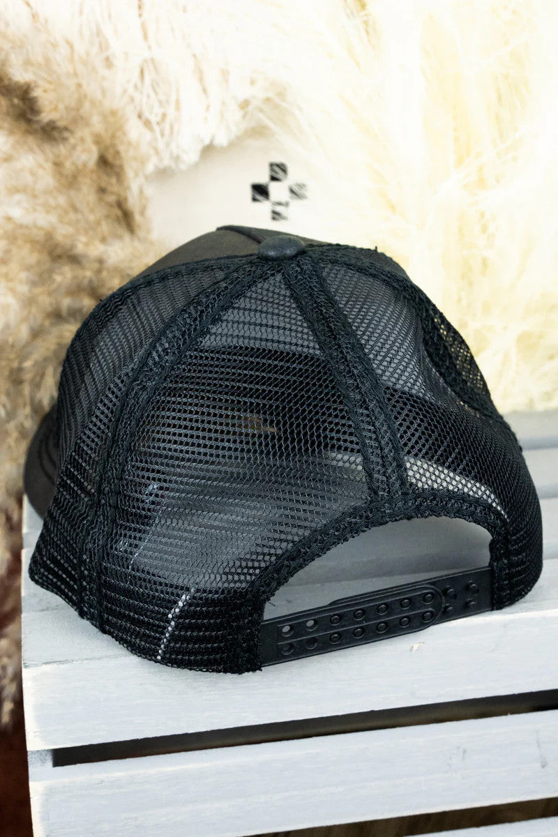 Black mesh cap on a white surface with a textured beige background
